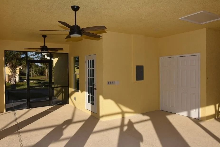 Yellow-painted patio with two ceiling fans, glass screen enclosure, white door, and folding closet doors.