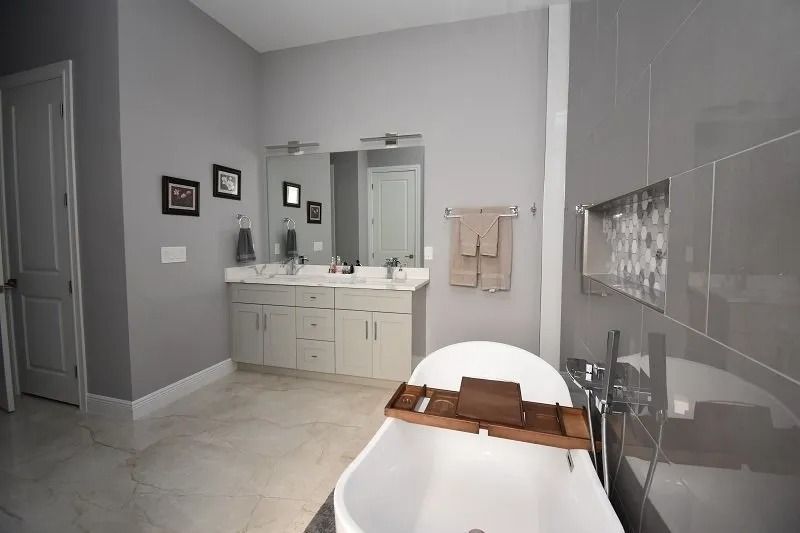 Gray and white bathroom with a freestanding tub, double vanity, and shower.