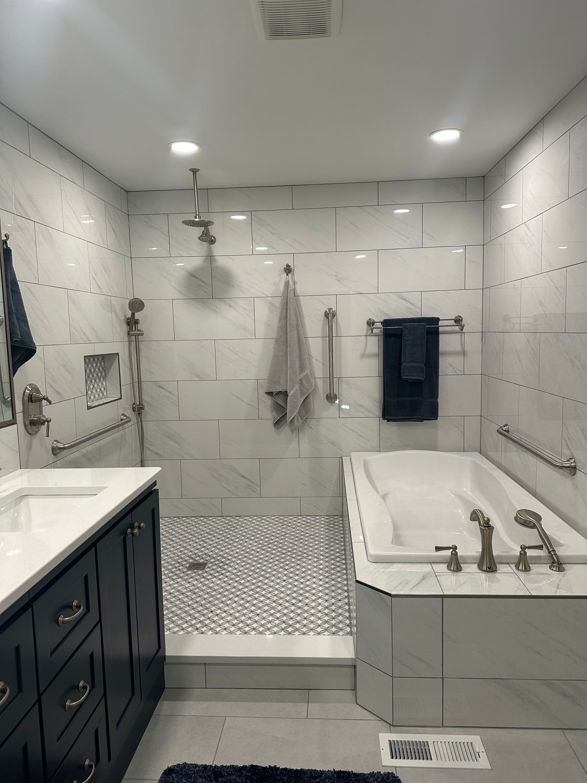 Bright white bathroom with a walk-in shower, double vanity, and black towel hooks