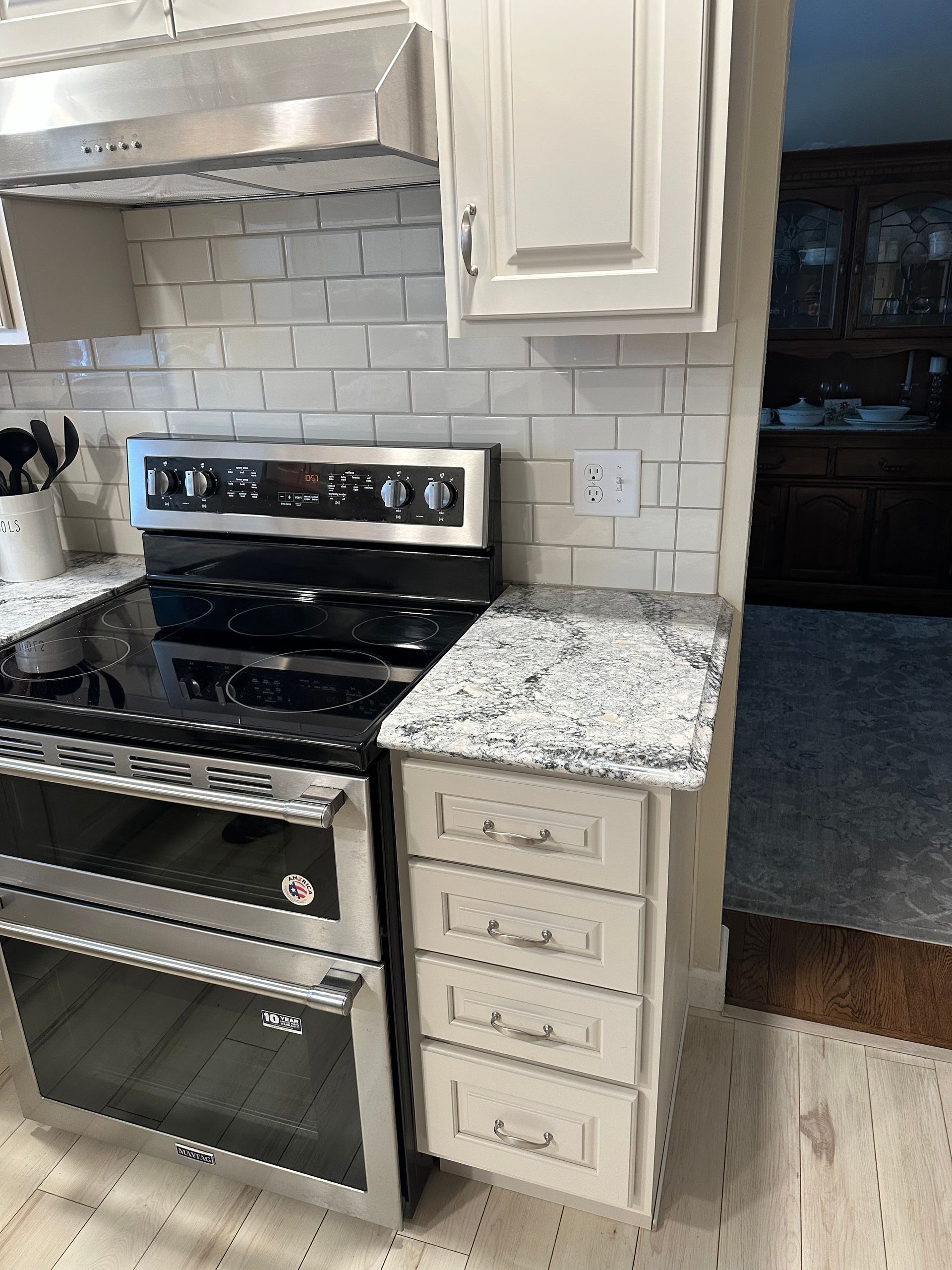 Kitchen with black stove, white cabinets, and granite countertop beside a dark doorway.
