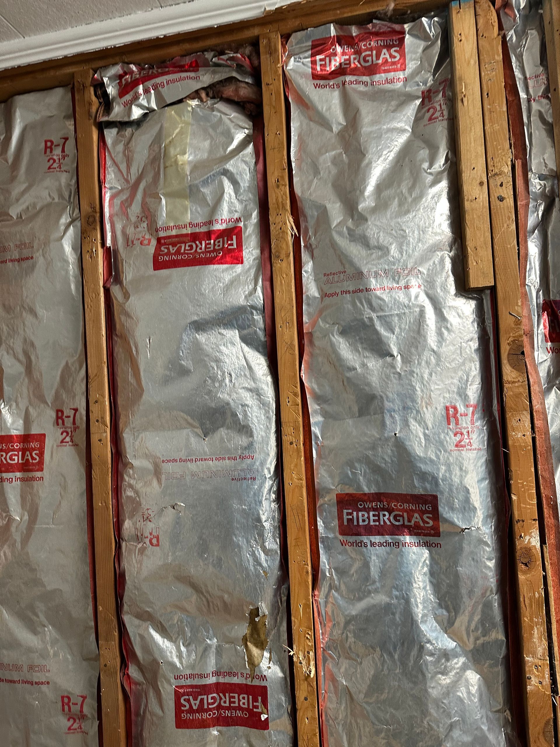Foil-wrapped wall insulation between wooden studs in an unfinished interior wall