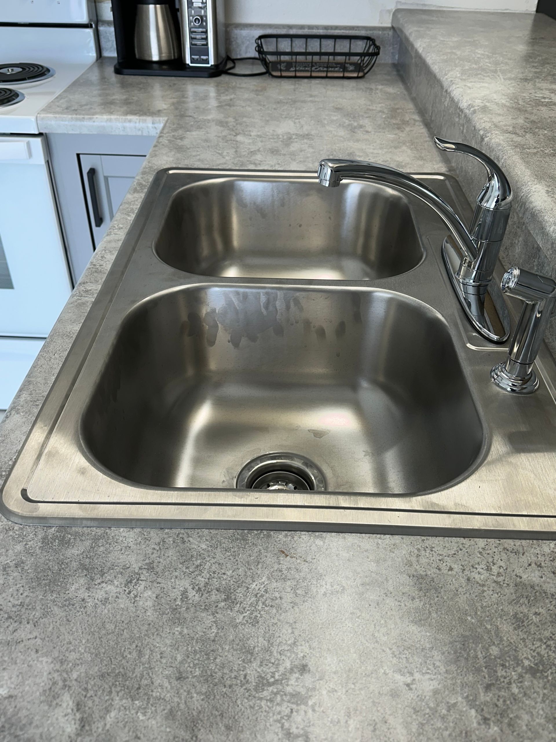 Double kitchen sink with chrome faucet on a gray countertop