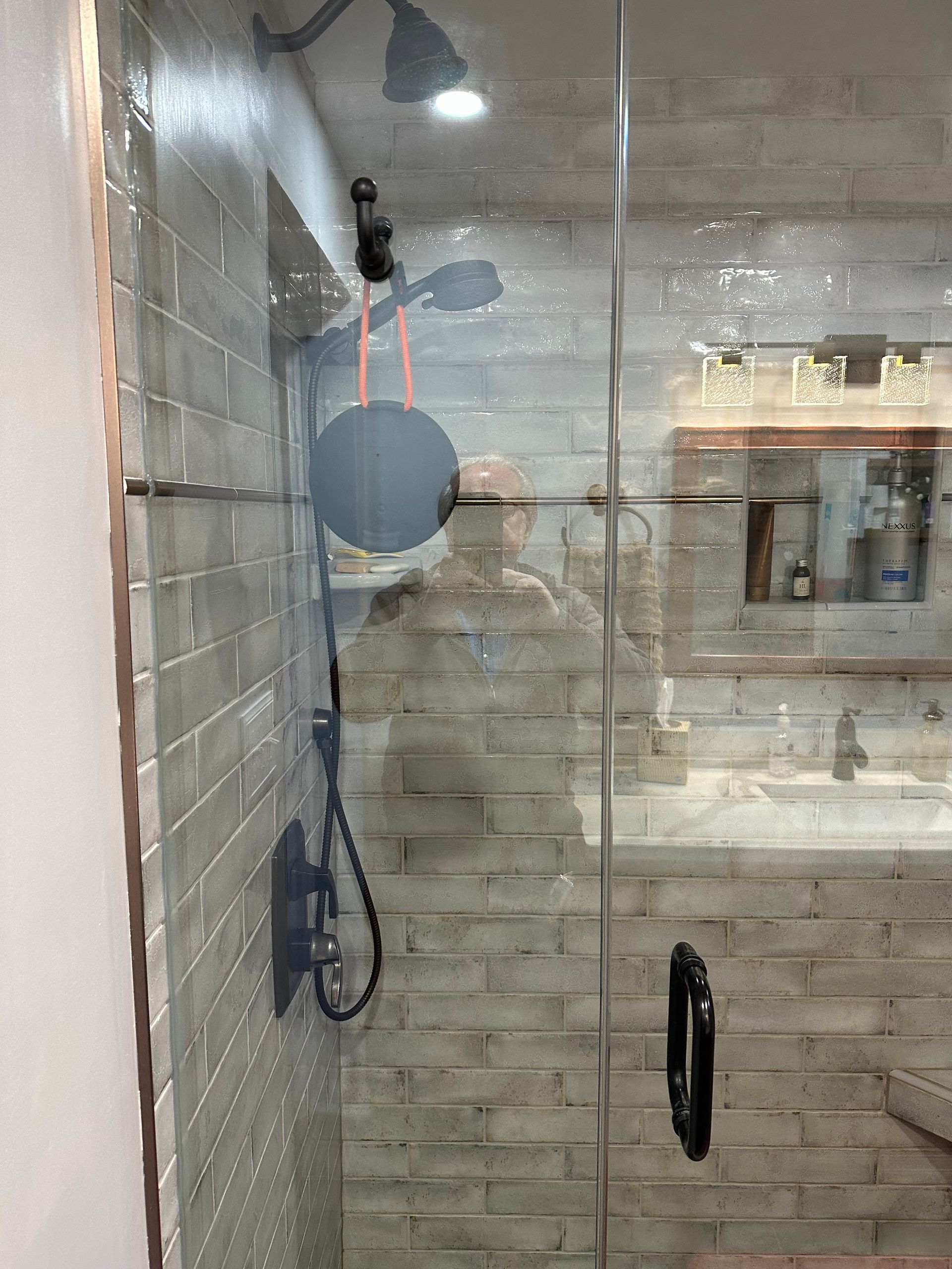 Modern bathroom shower with glass enclosure, gray tile walls, and black shower fixtures