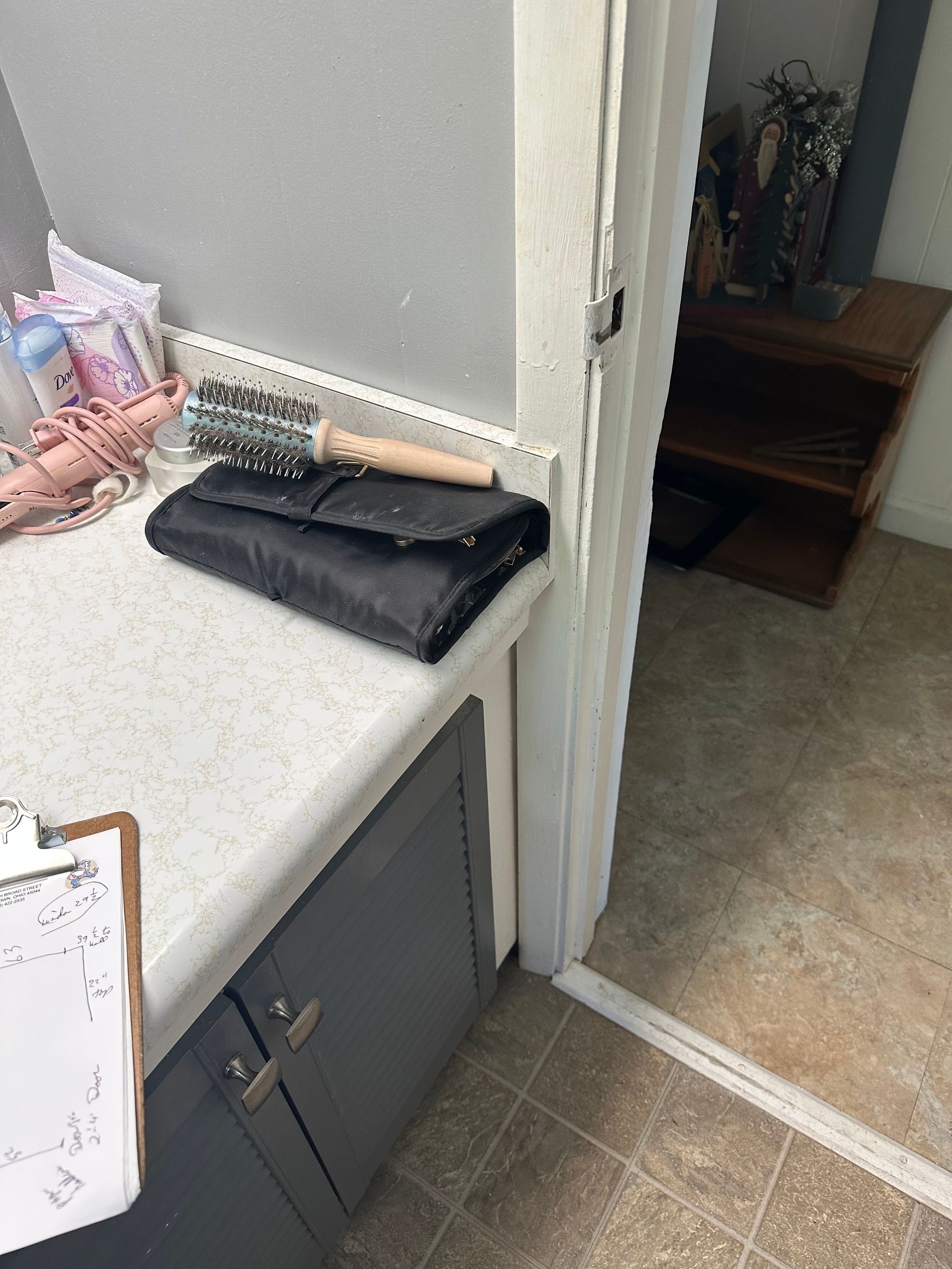 Kitchen counter with folded black towels, a white clipboard, and an open doorway to a hallway.
