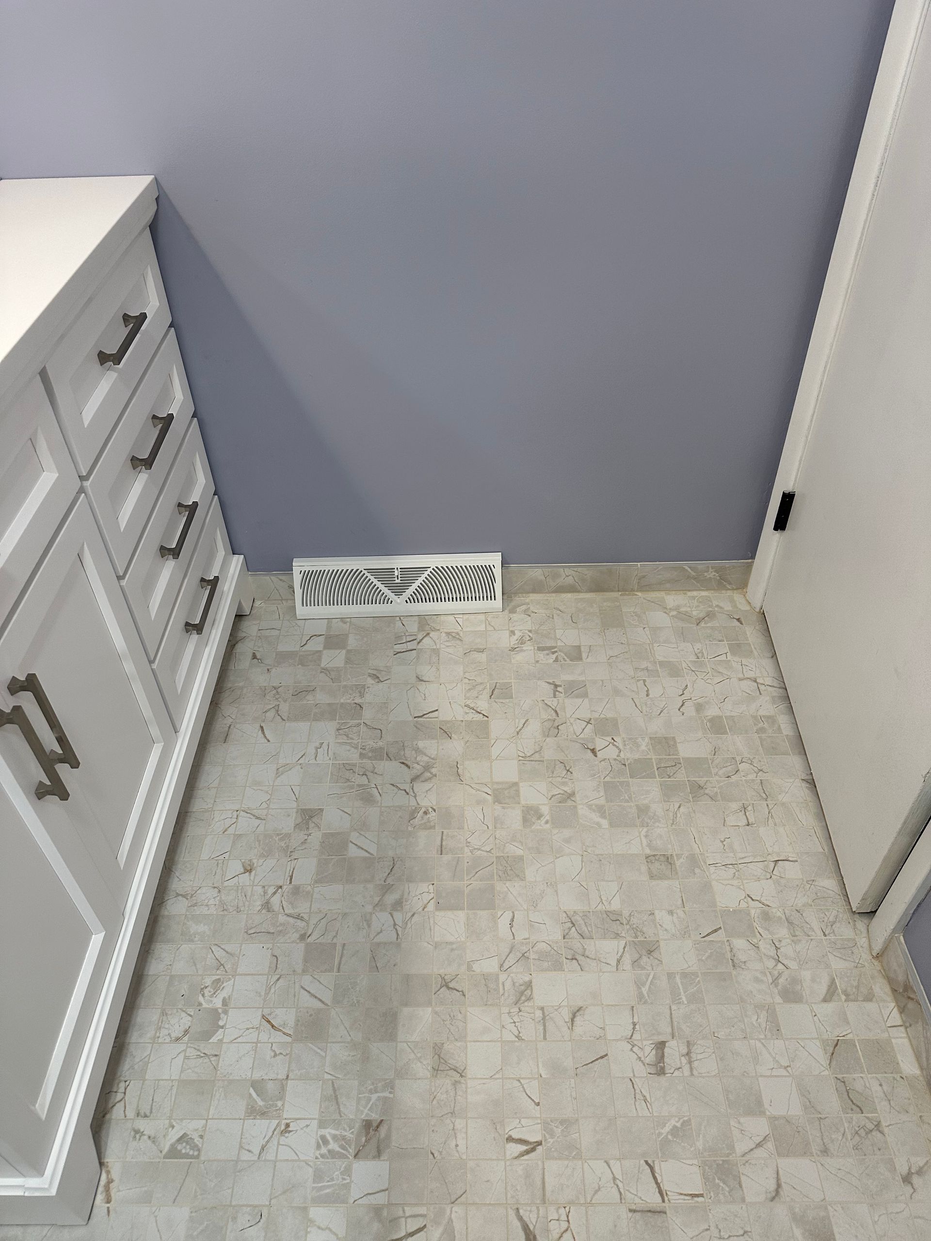Small bathroom with lavender walls, white cabinet, tiled floor, and a floor vent.