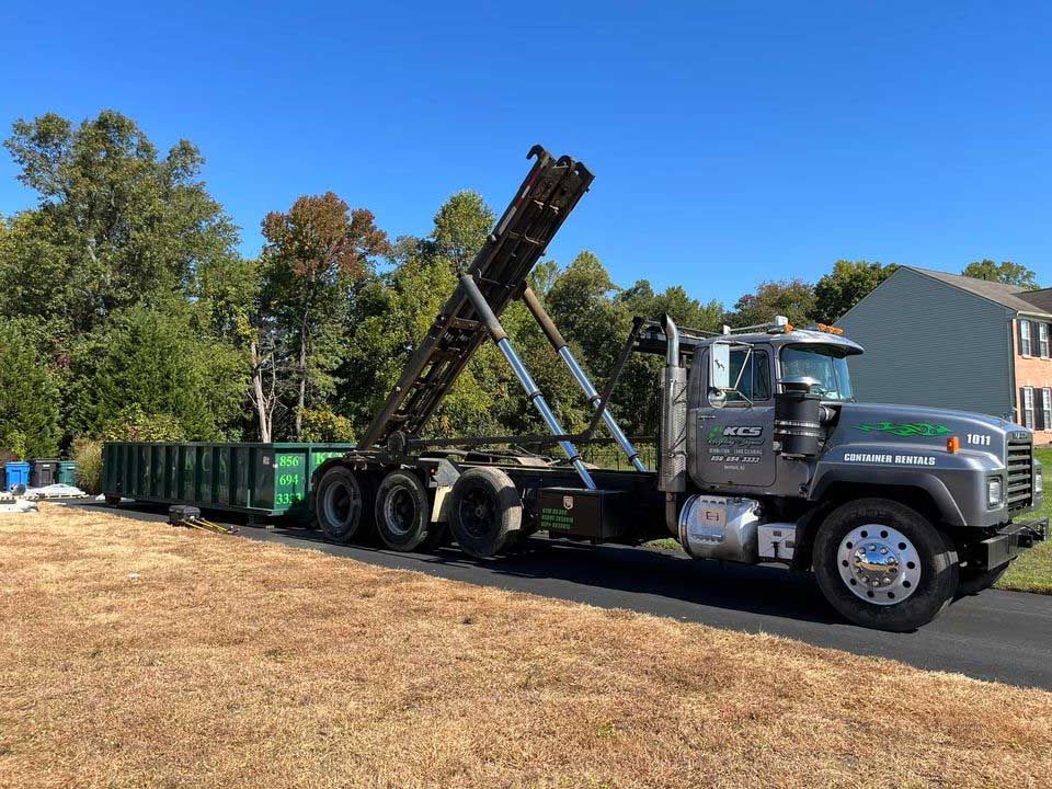 A dump truck is parked on the side of the road next to a house.
