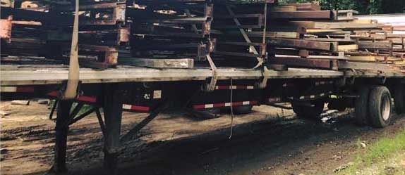 A trailer filled with wooden pallets is parked on the side of the road.