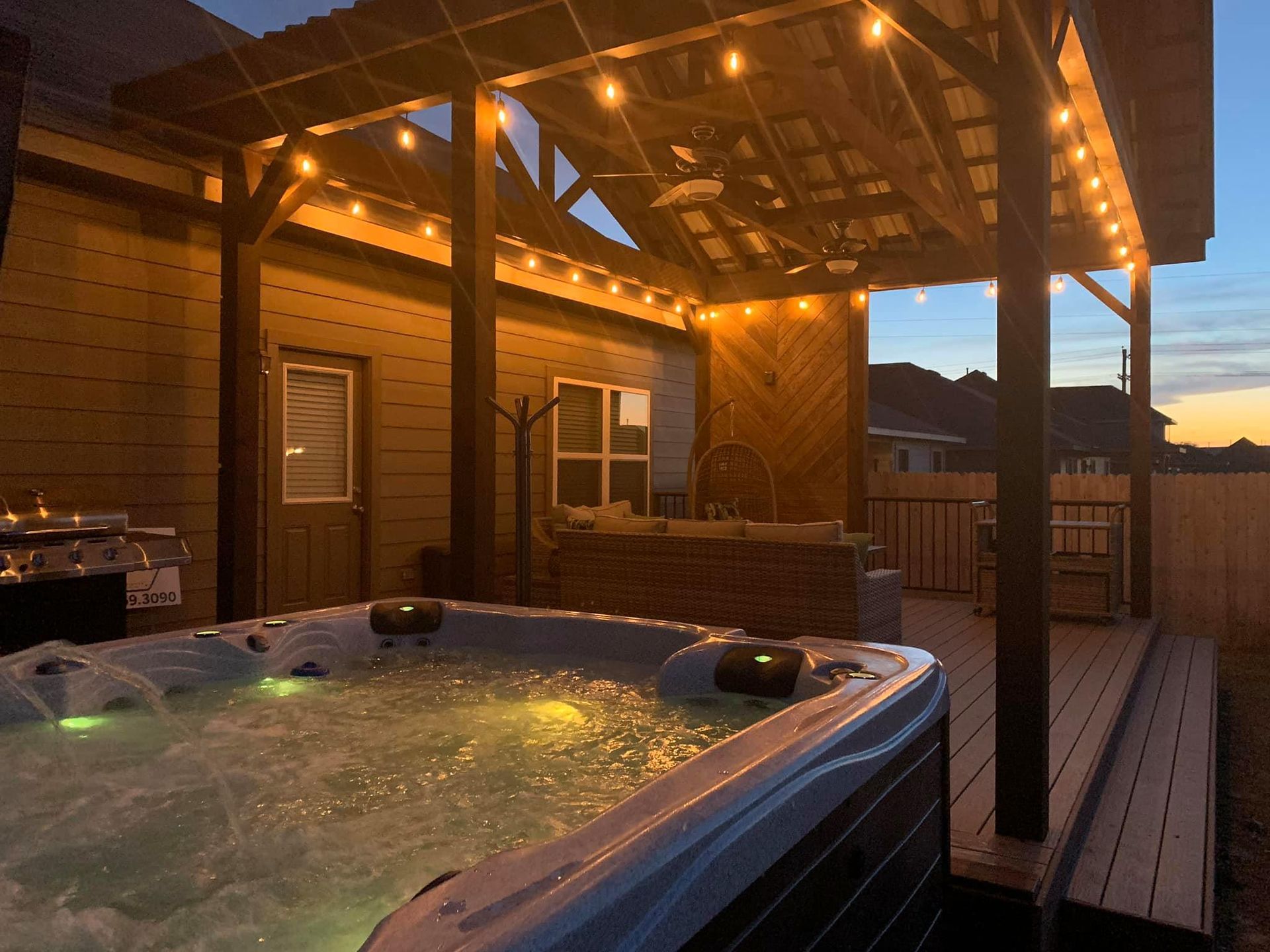 A hot tub is sitting on a deck under a pergola.