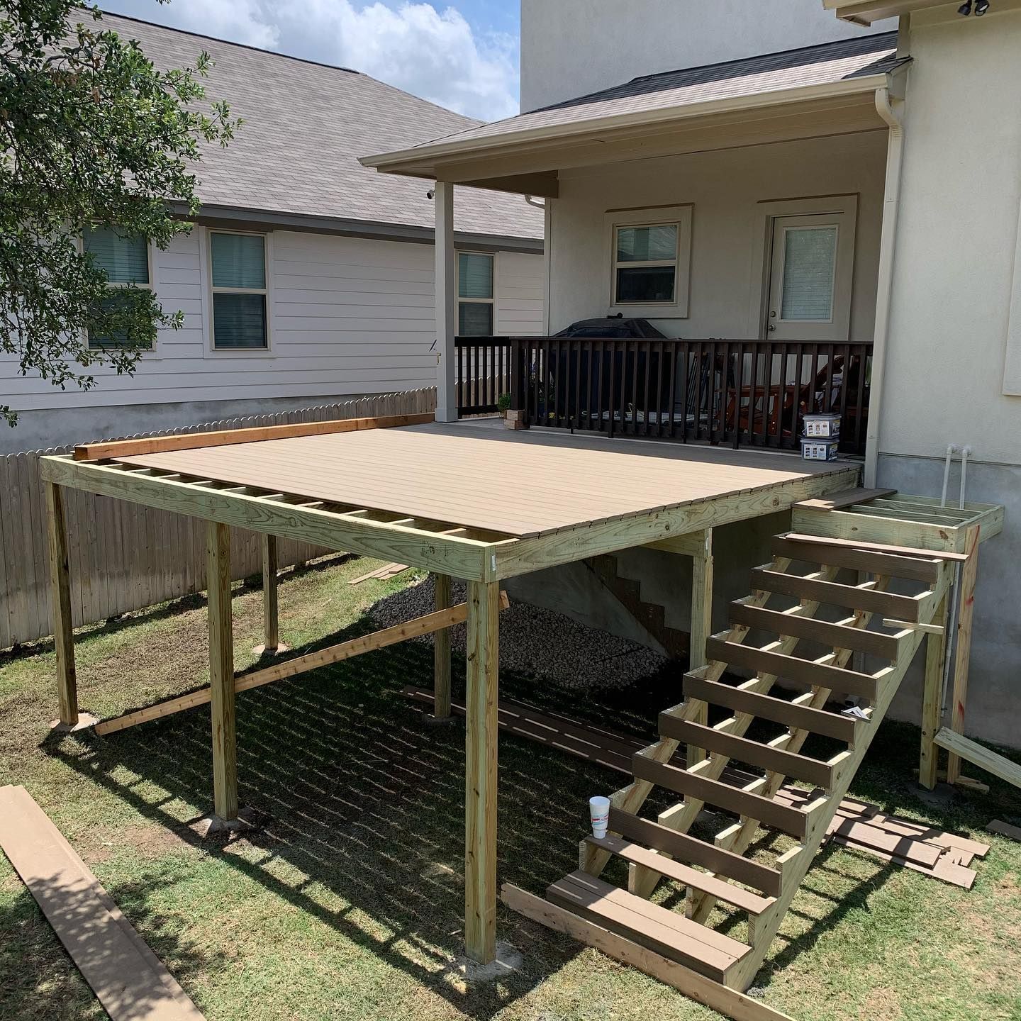 A wooden deck is being built in the backyard of a house.