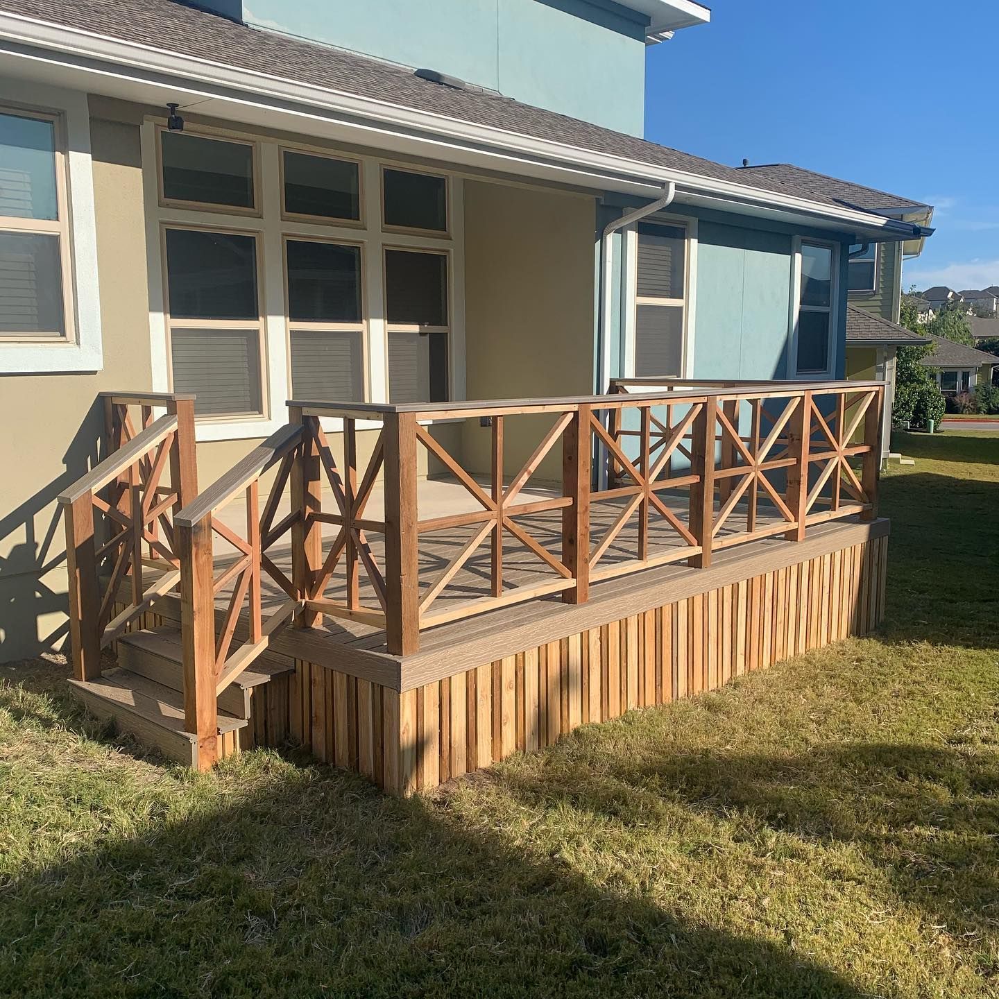 A wooden deck with stairs is in front of a house.