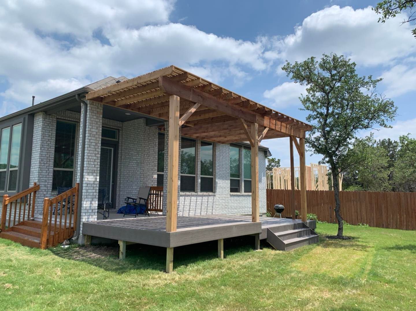 A house with a deck and a pergola in the backyard.