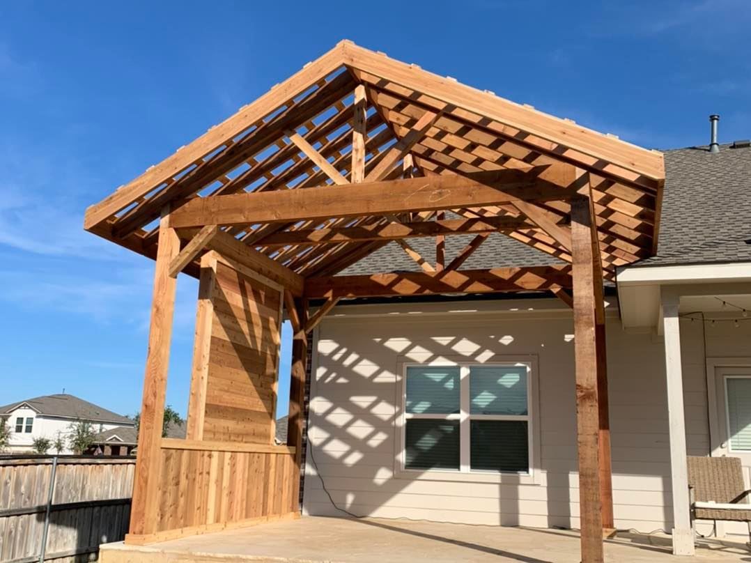 A wooden pergola is being built on the side of a house.