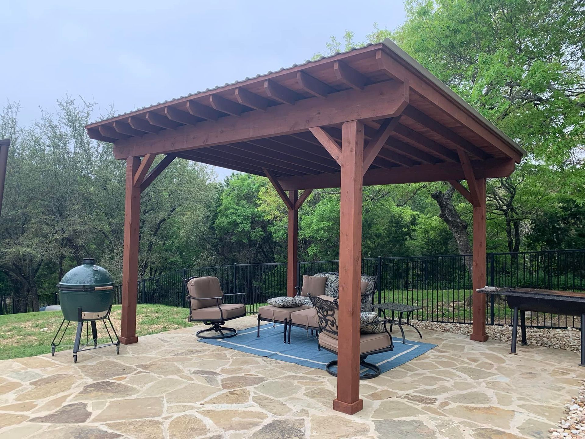 A wooden pergola is sitting on top of a stone patio.
