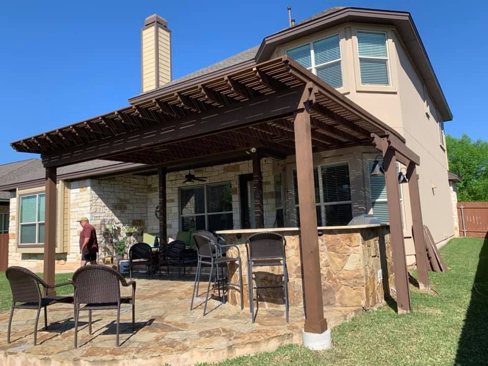 A large house with a pergola and chairs in front of it.