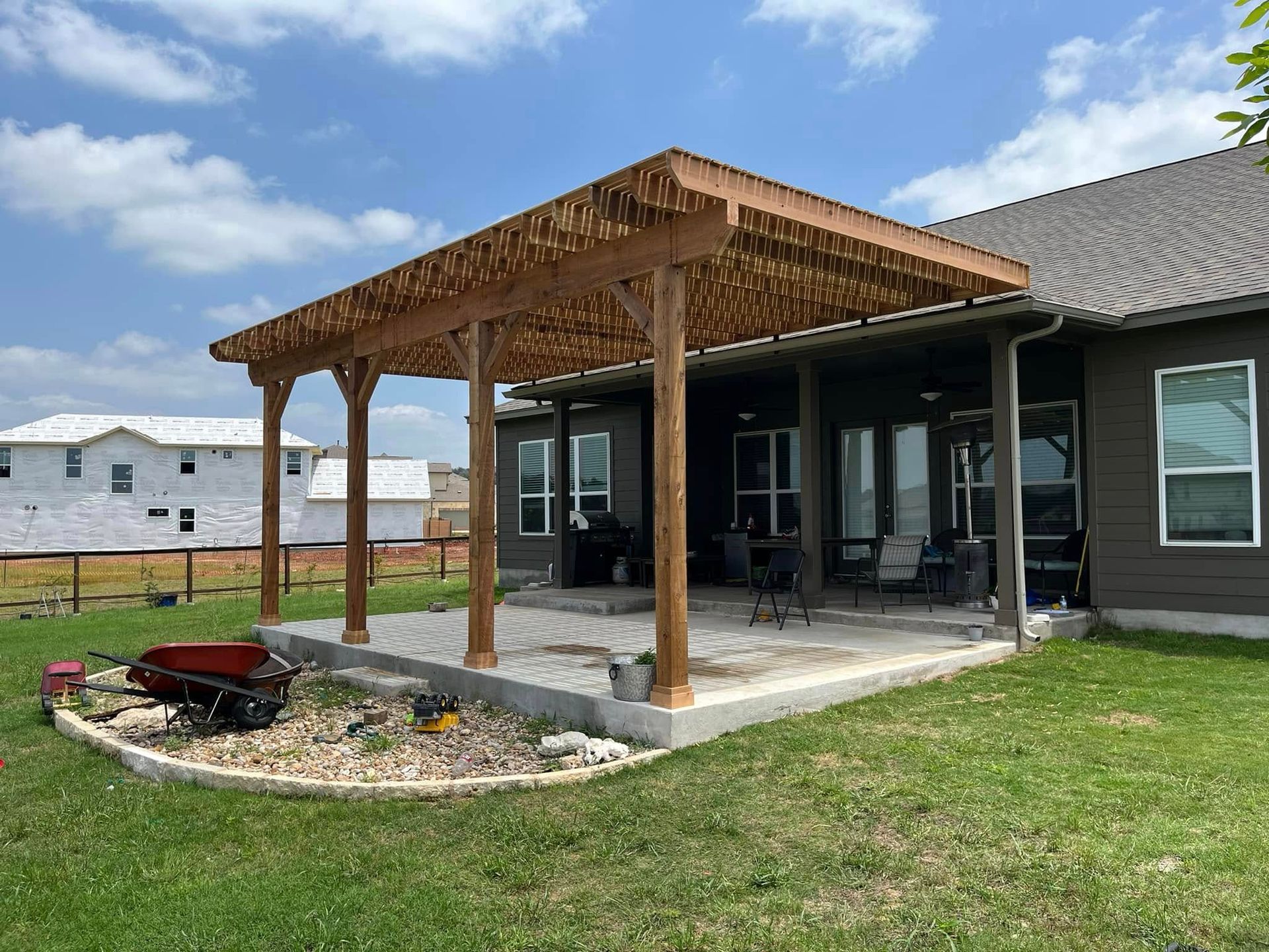 A house with a wooden pergola over a patio in the backyard.