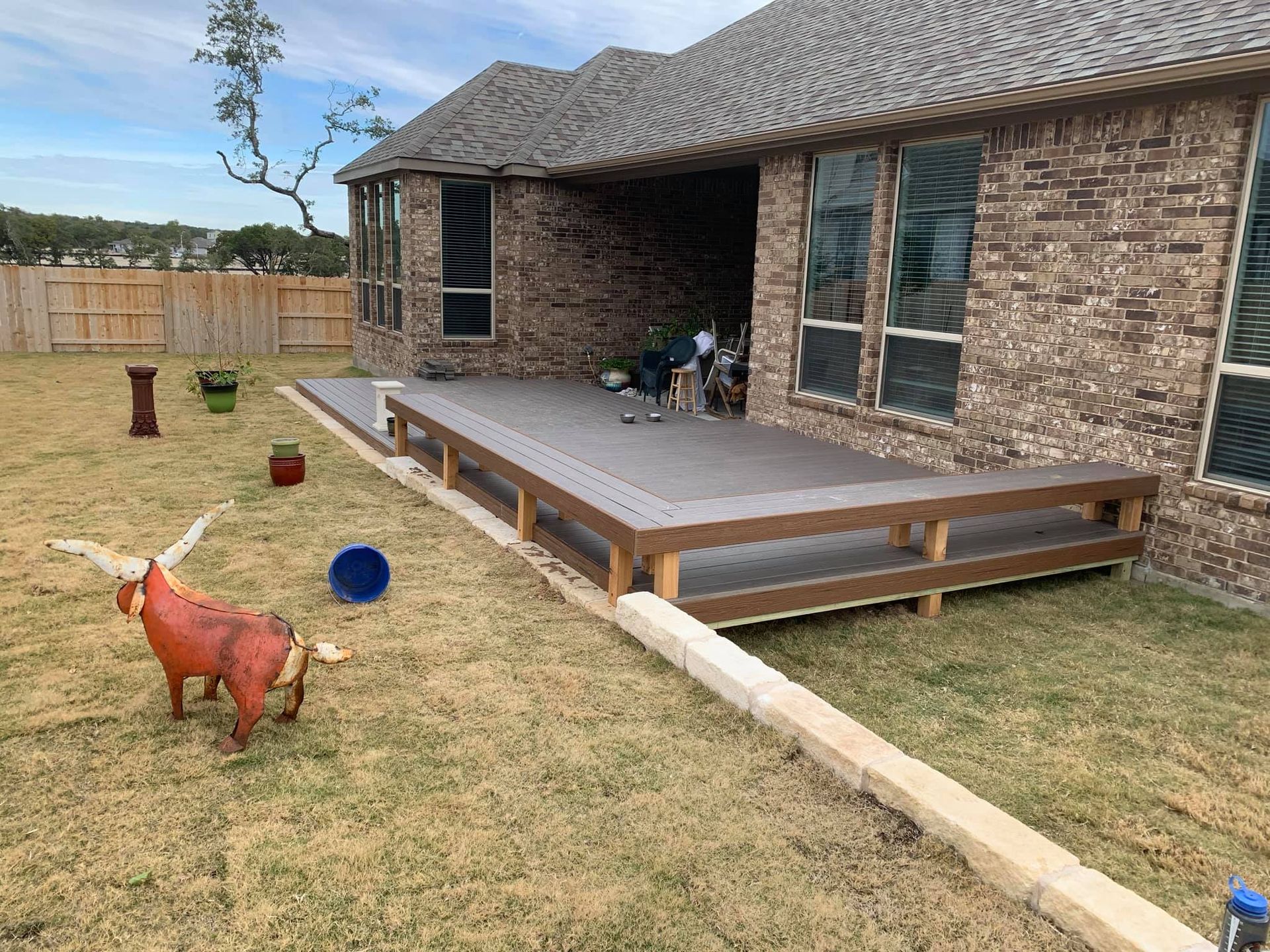 There is a statue of a bull in the grass in front of a brick house.