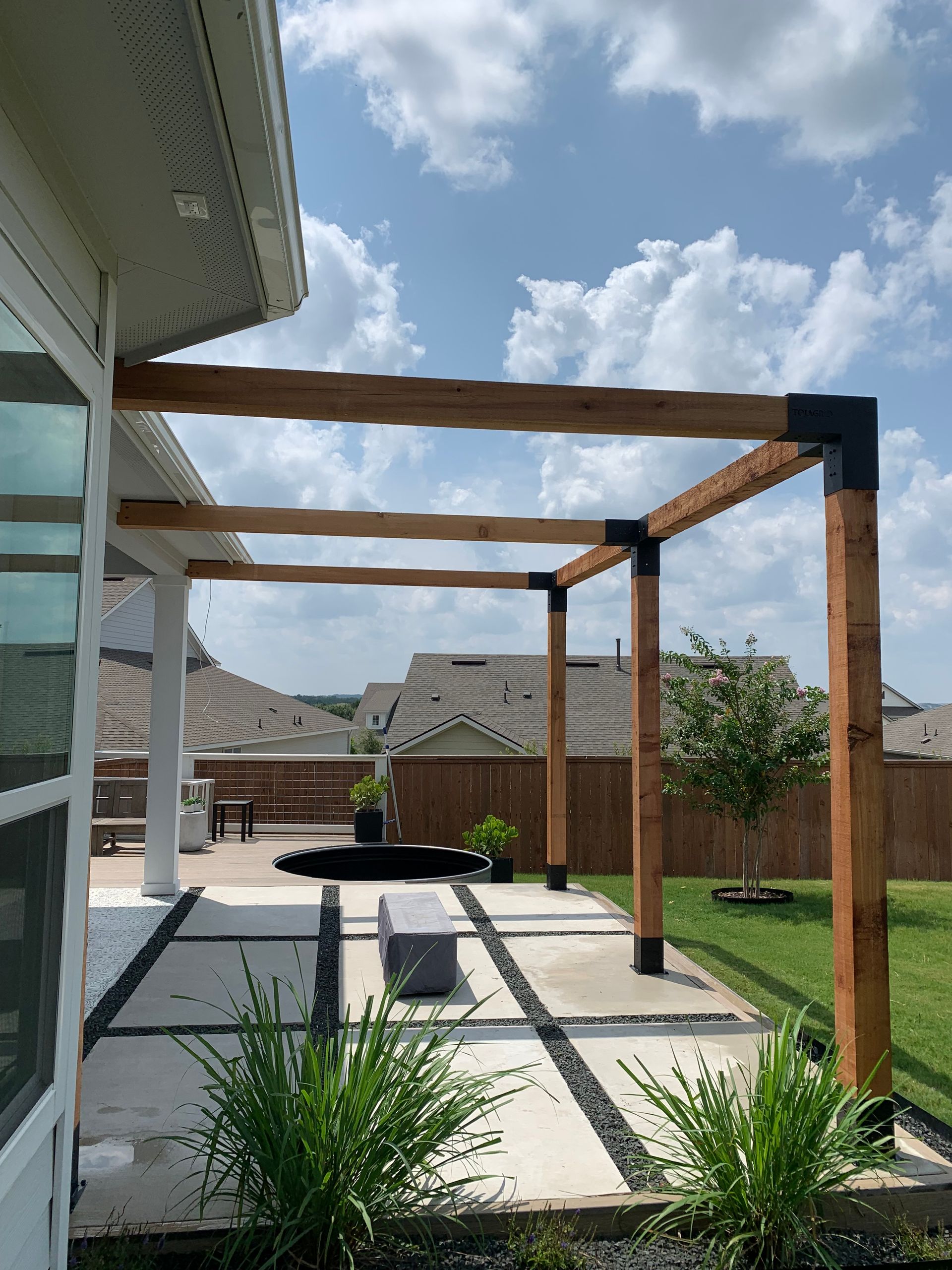 A wooden pergola is sitting in the backyard of a house.