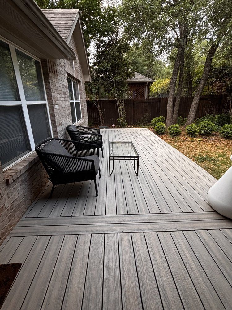 A wooden deck with chairs and a table in front of a house.
