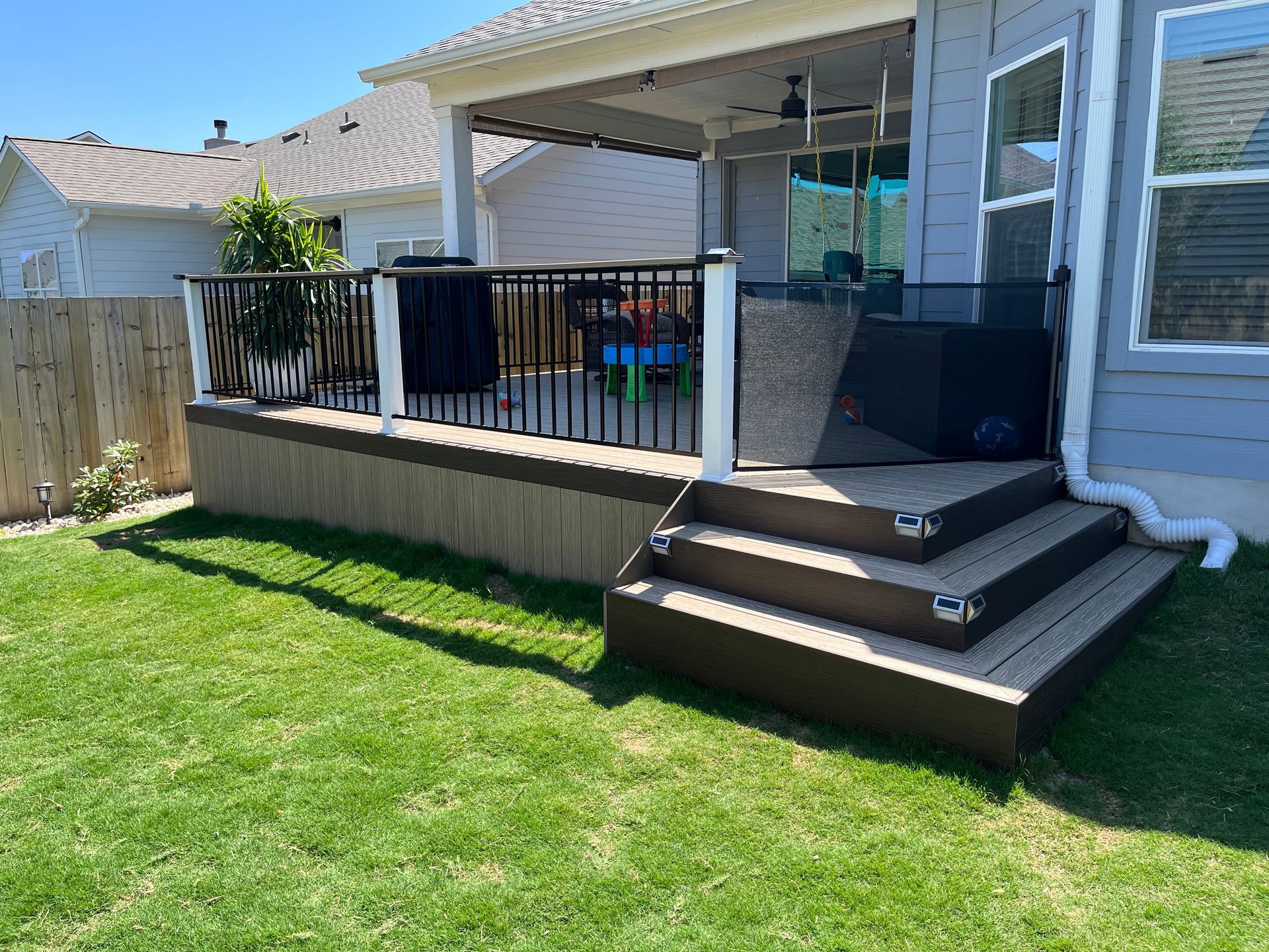 A deck with stairs leading up to it is in the backyard of a house.
