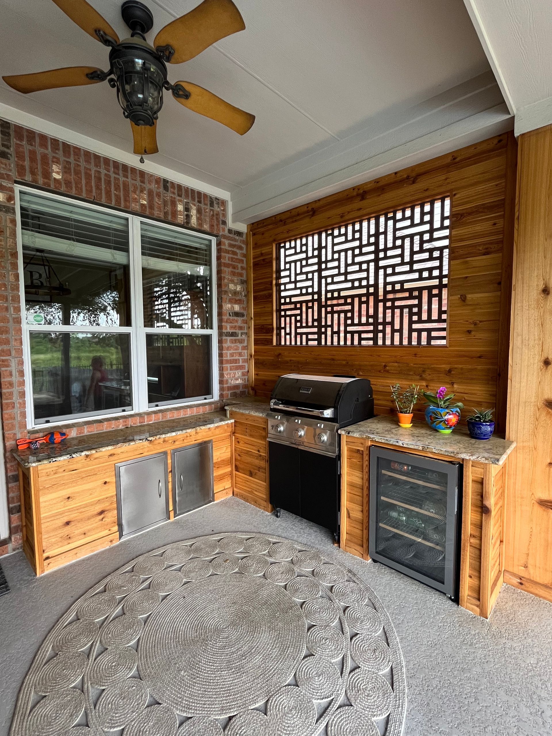 A kitchen with a grill, refrigerator, and ceiling fan.