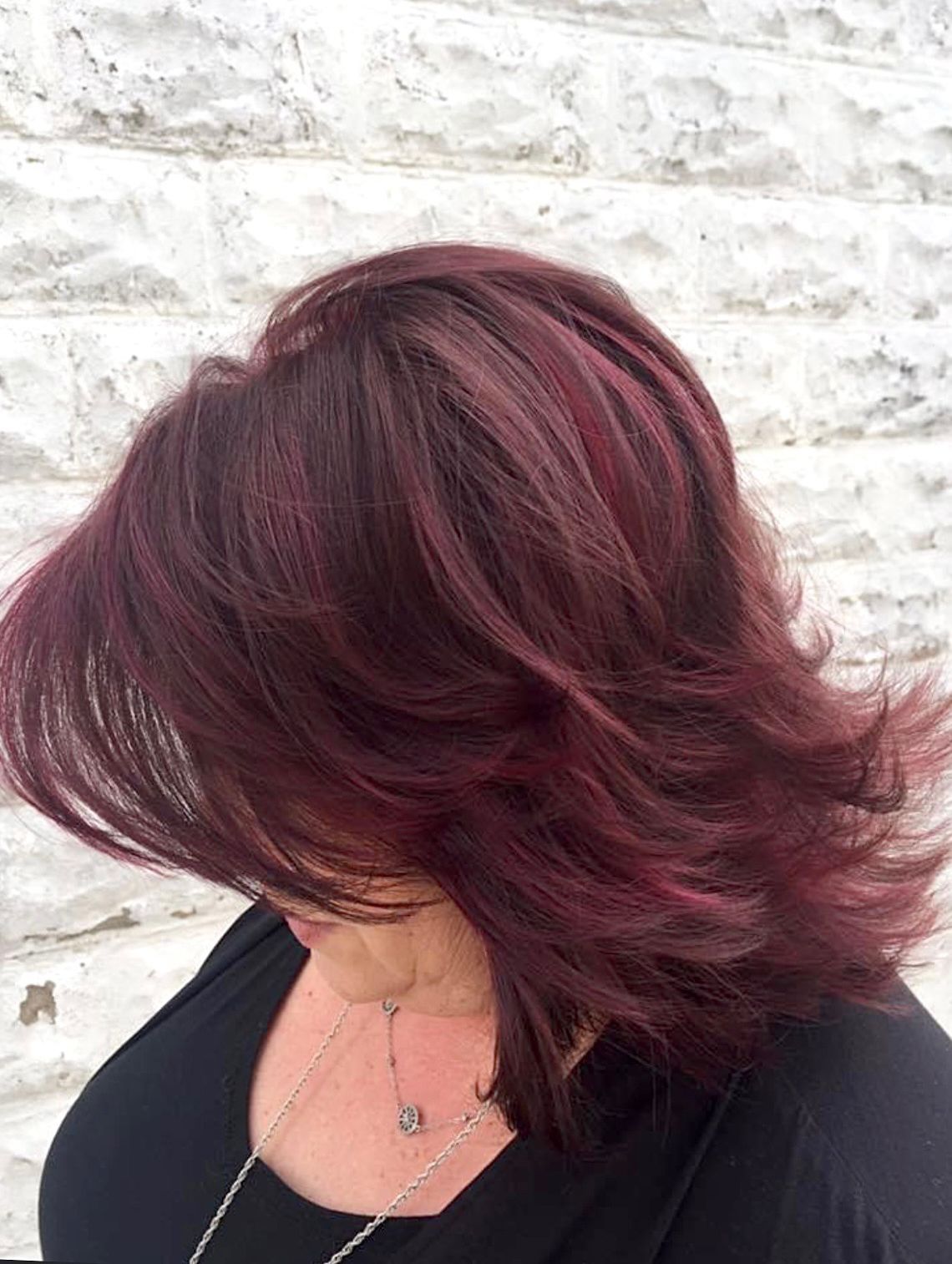 a woman with red hair is wearing a black shirt and a necklace