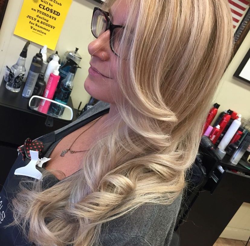 a woman with long blonde hair is standing in front of a sign that says closed