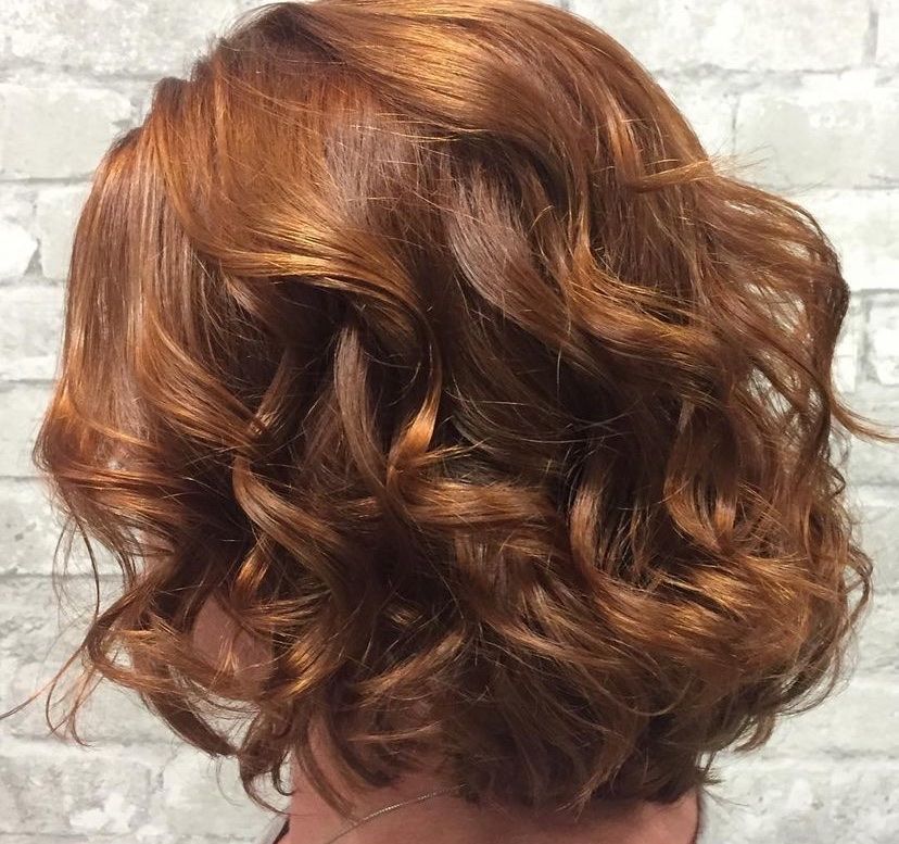 a close up of a woman 's hair with a brick wall in the background
