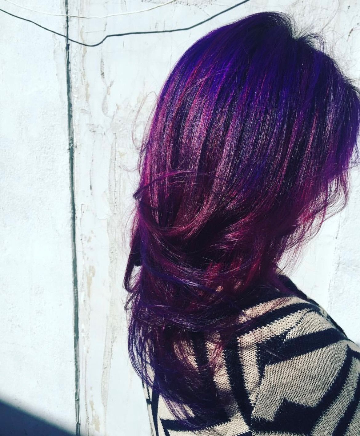a woman with purple hair is wearing a striped sweater