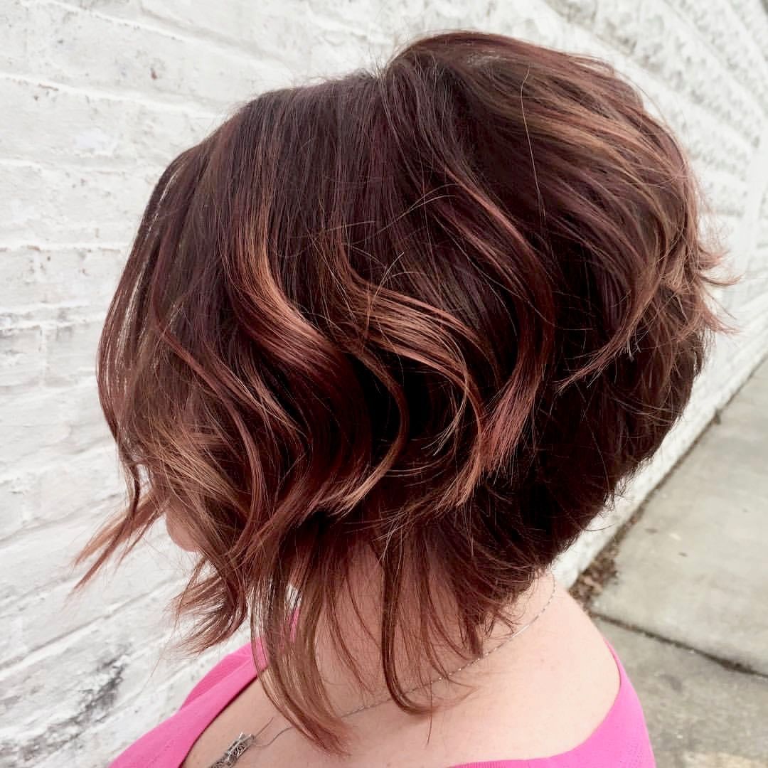 a woman with short brown hair is wearing a pink shirt