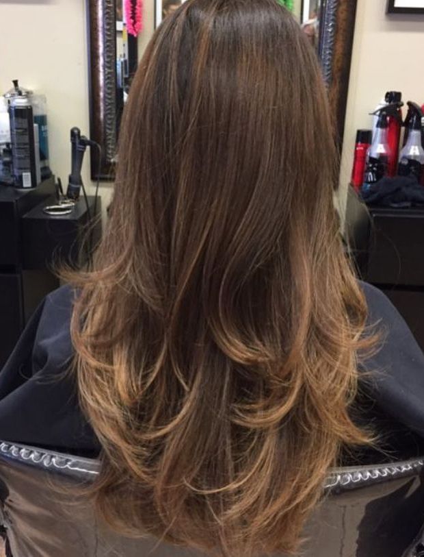 a woman with long hair is sitting in a chair at a hair salon