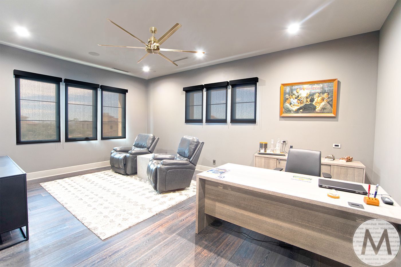 Modern office with two recliners, desk, rug, and artwork.