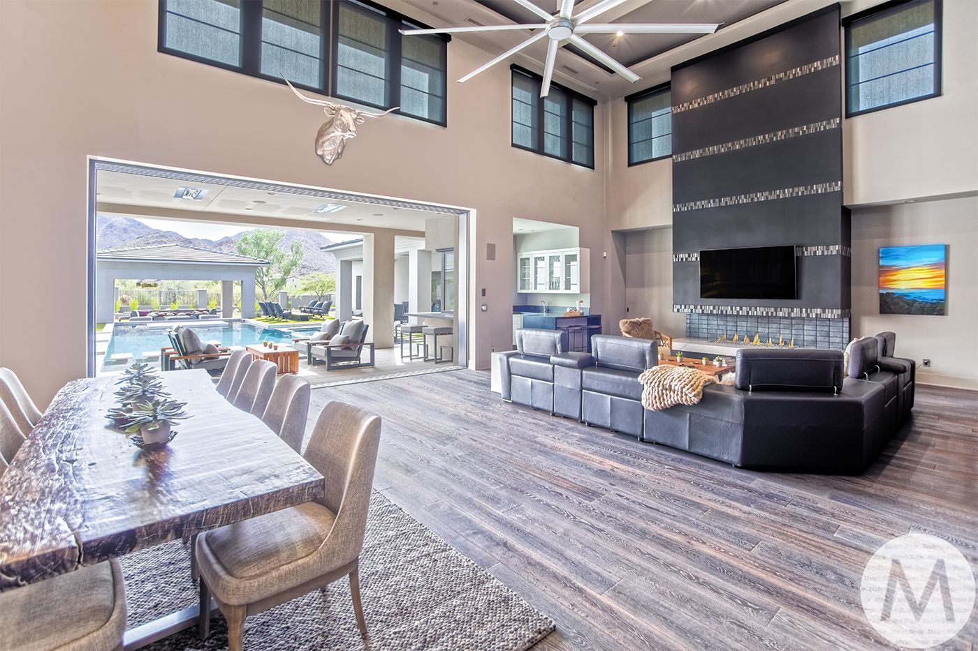 Spacious modern living room with open doors to a pool area, large dining table, and fireplace.