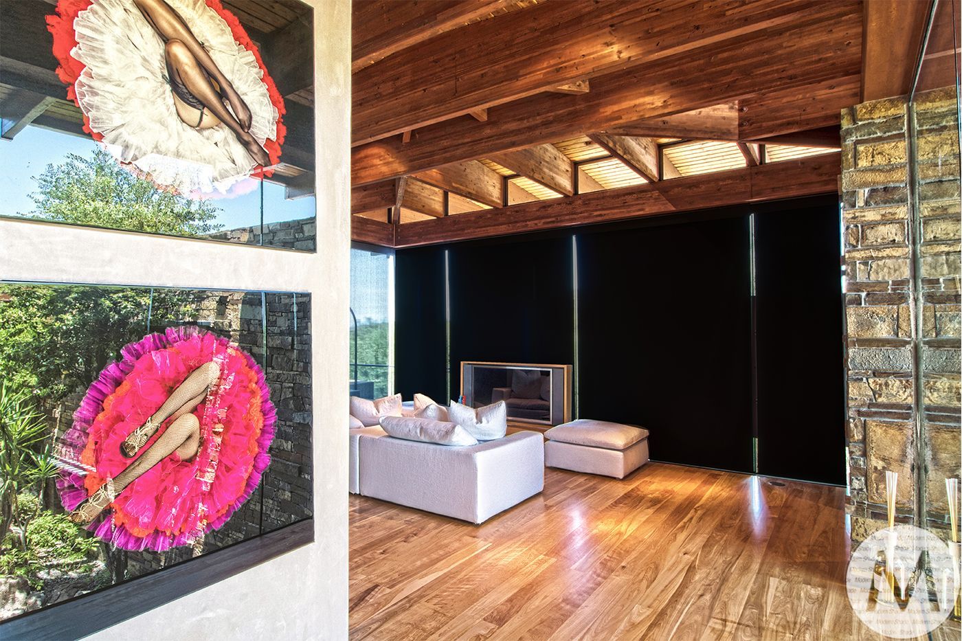 Modern living room with art, wood beams, and glass block wall.