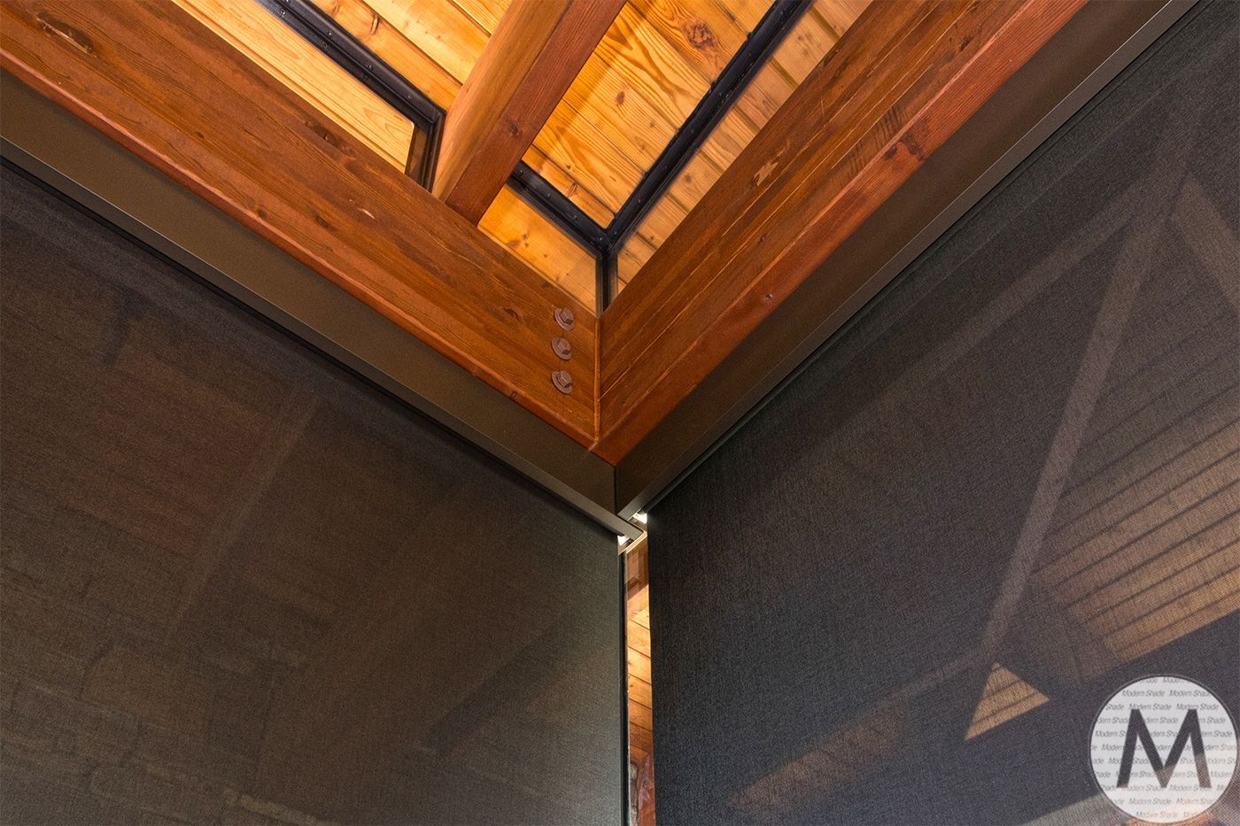 Corner of a wooden structure with a dark mesh screen. Angled view with wooden beams.