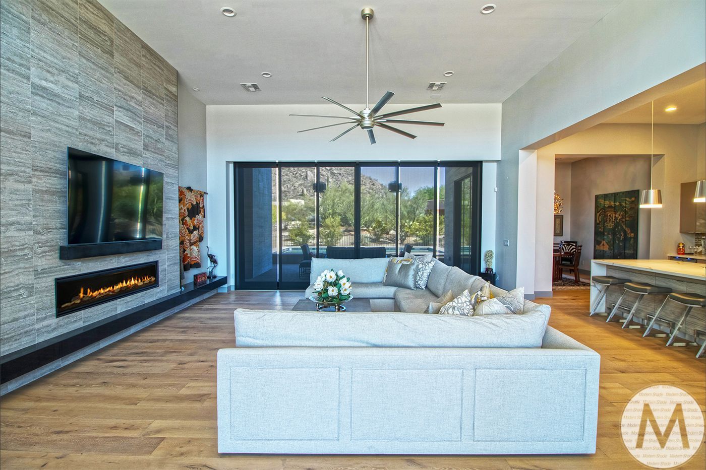 Modern living room with stone accent wall, fireplace, and expansive windows overlooking greenery.