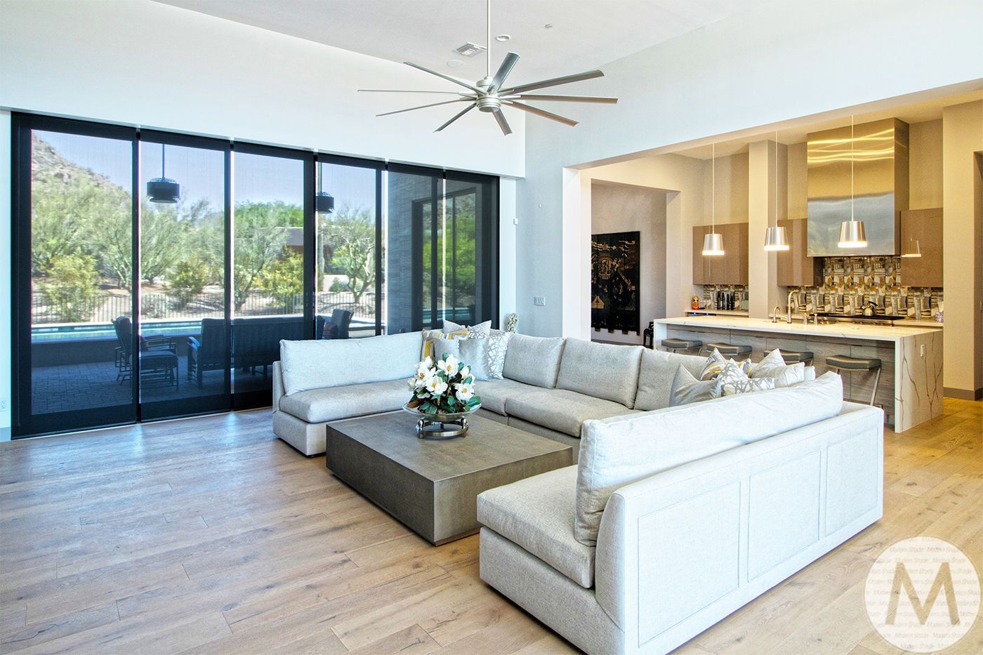 Modern living room with large sectional sofa, open to kitchen, and sliding glass doors to a patio.