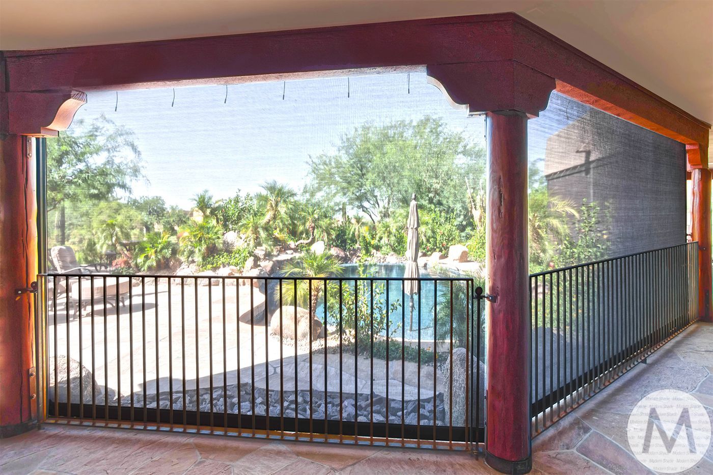 Balcony with black mesh screens and a pool view. Wooden posts and a black railing are visible.