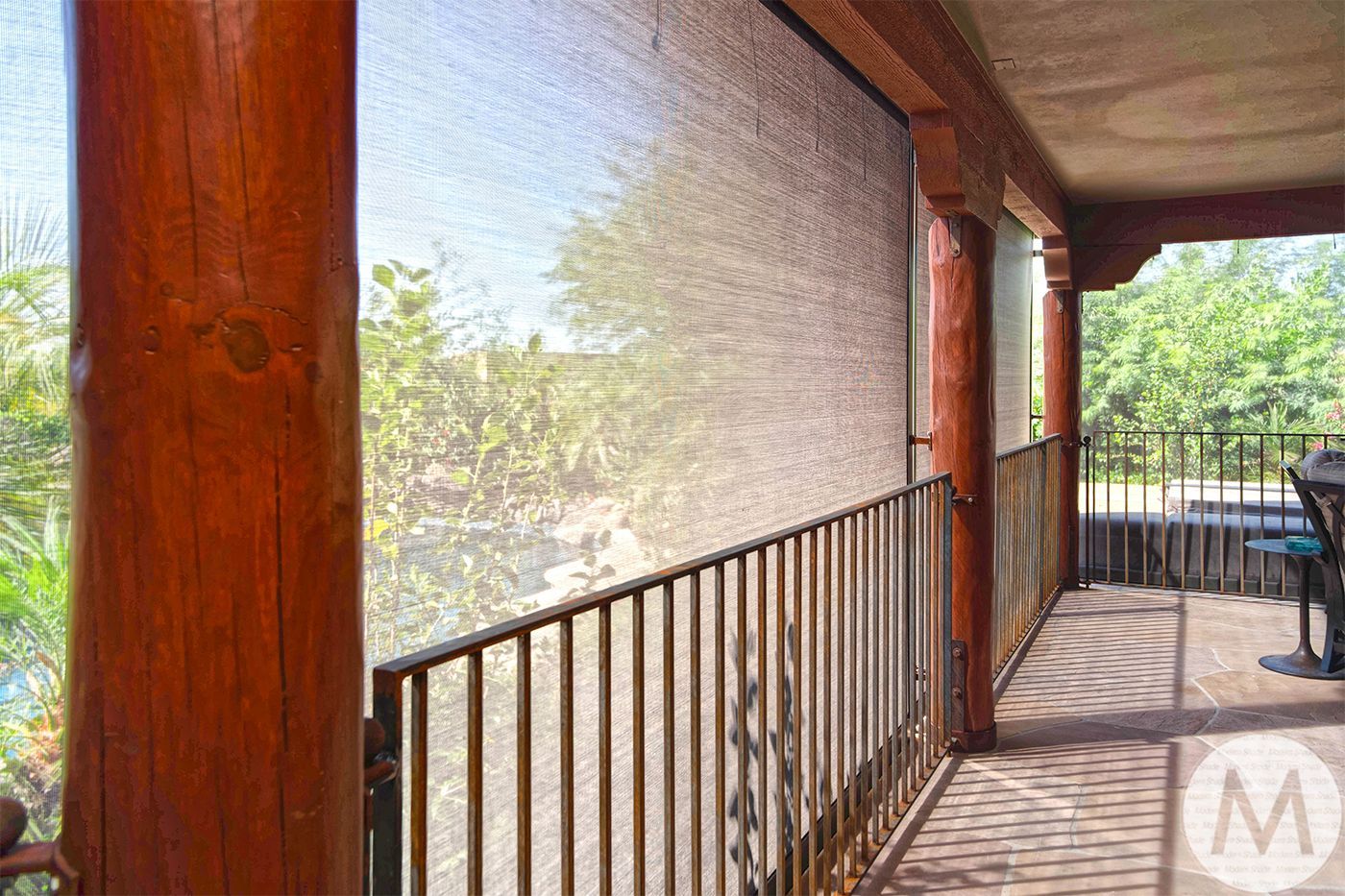 Balcony with a brown railing, wooden pillars, and a sun screen.