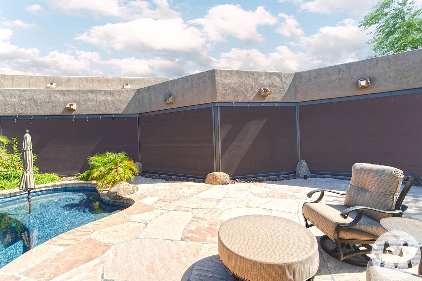 Patio with a pool, stone floor, shaded seating area, and dark brown sun shades against a wall.