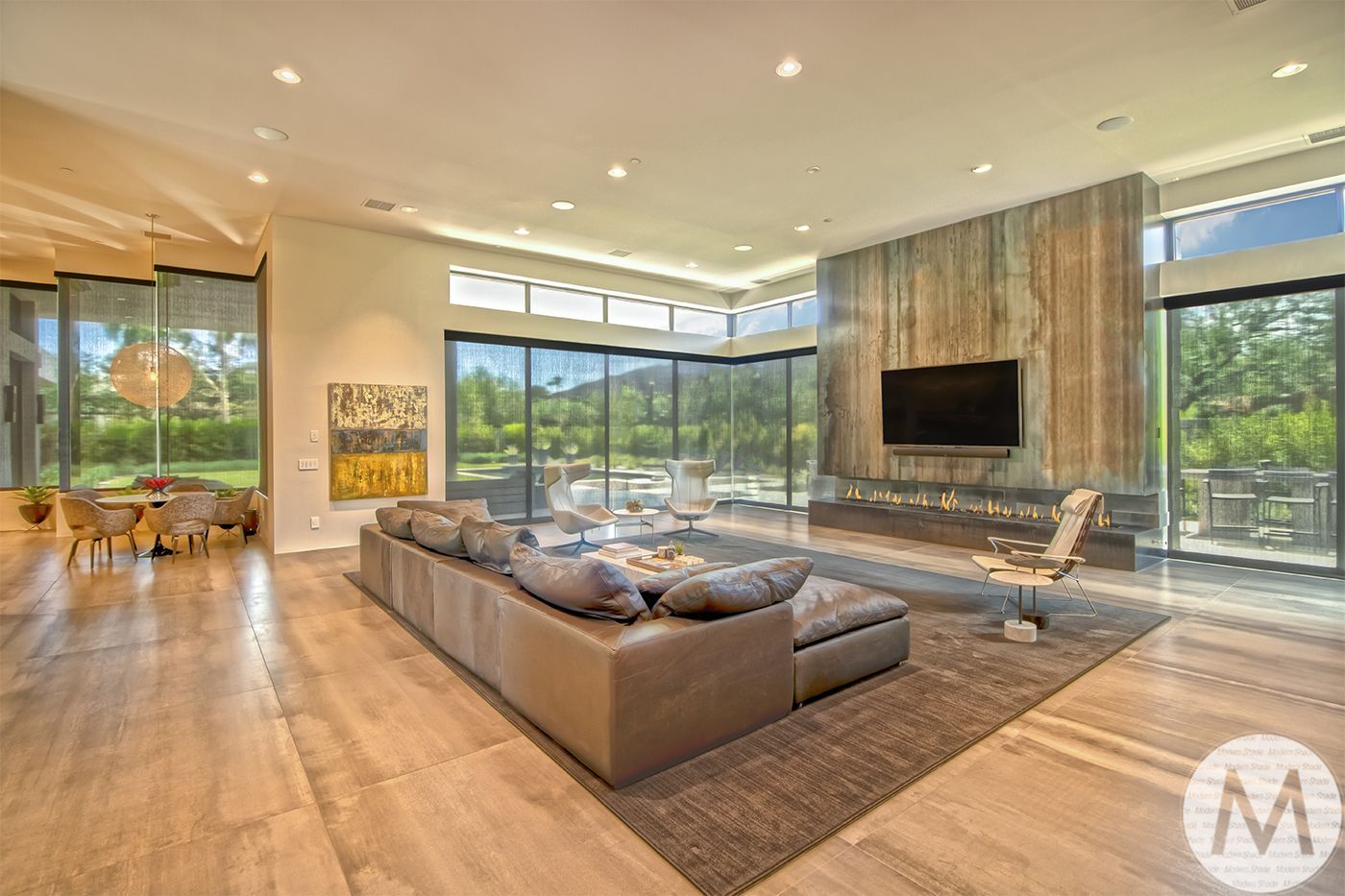 Modern living room with floor-to-ceiling windows, a large gray sofa, and a fireplace.
