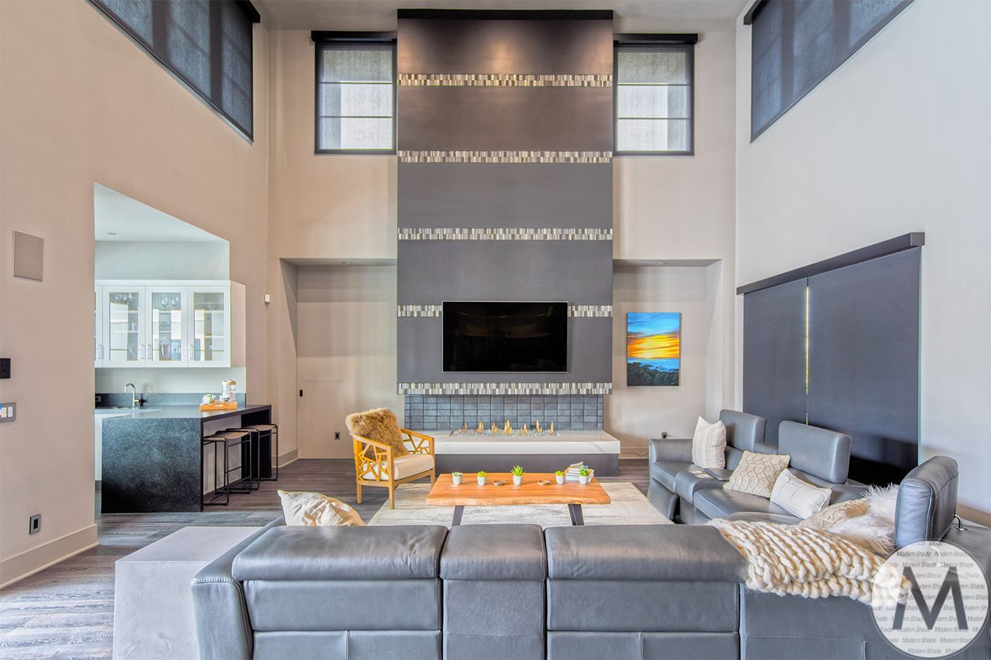 Modern living room with gray sectional, fireplace, and high ceilings.