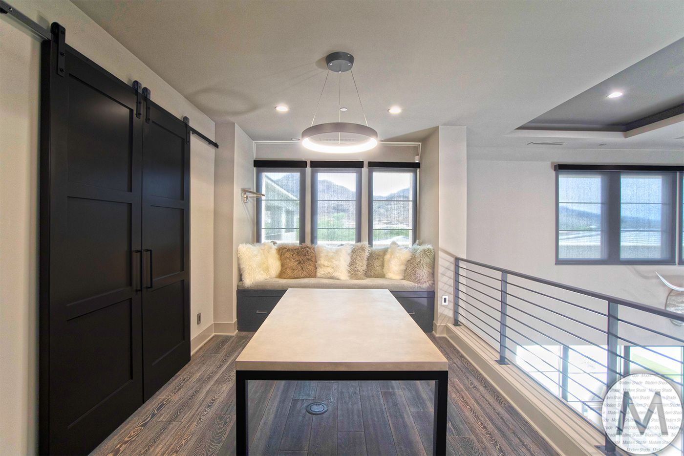 Interior with a black barn door, built-in bench with pillows, table, and a window with a view.