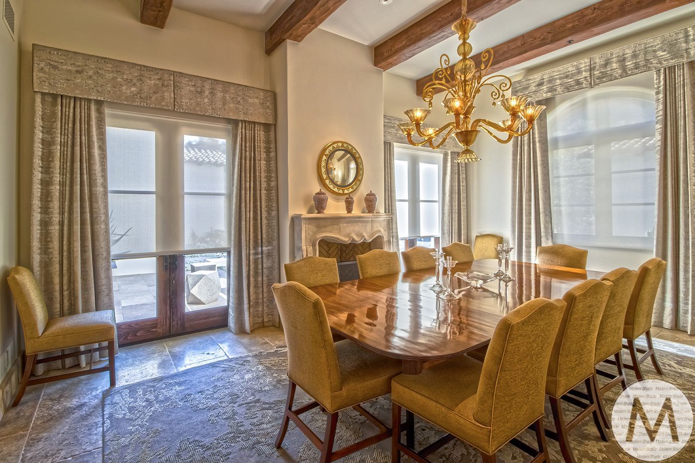 Elegant dining room with large table, chandelier, and upholstered chairs.