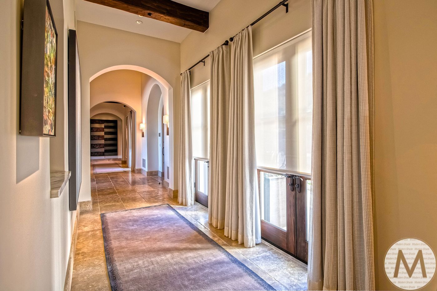 Hallway with arched doorways, wood-framed doors, and beige curtains. Marble floor with a purple runner.