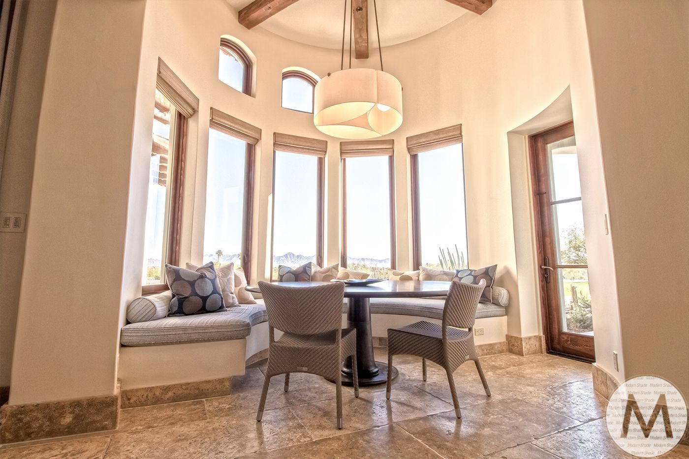 Breakfast nook with round table and chairs, window seat, bright lighting, and scenic view.