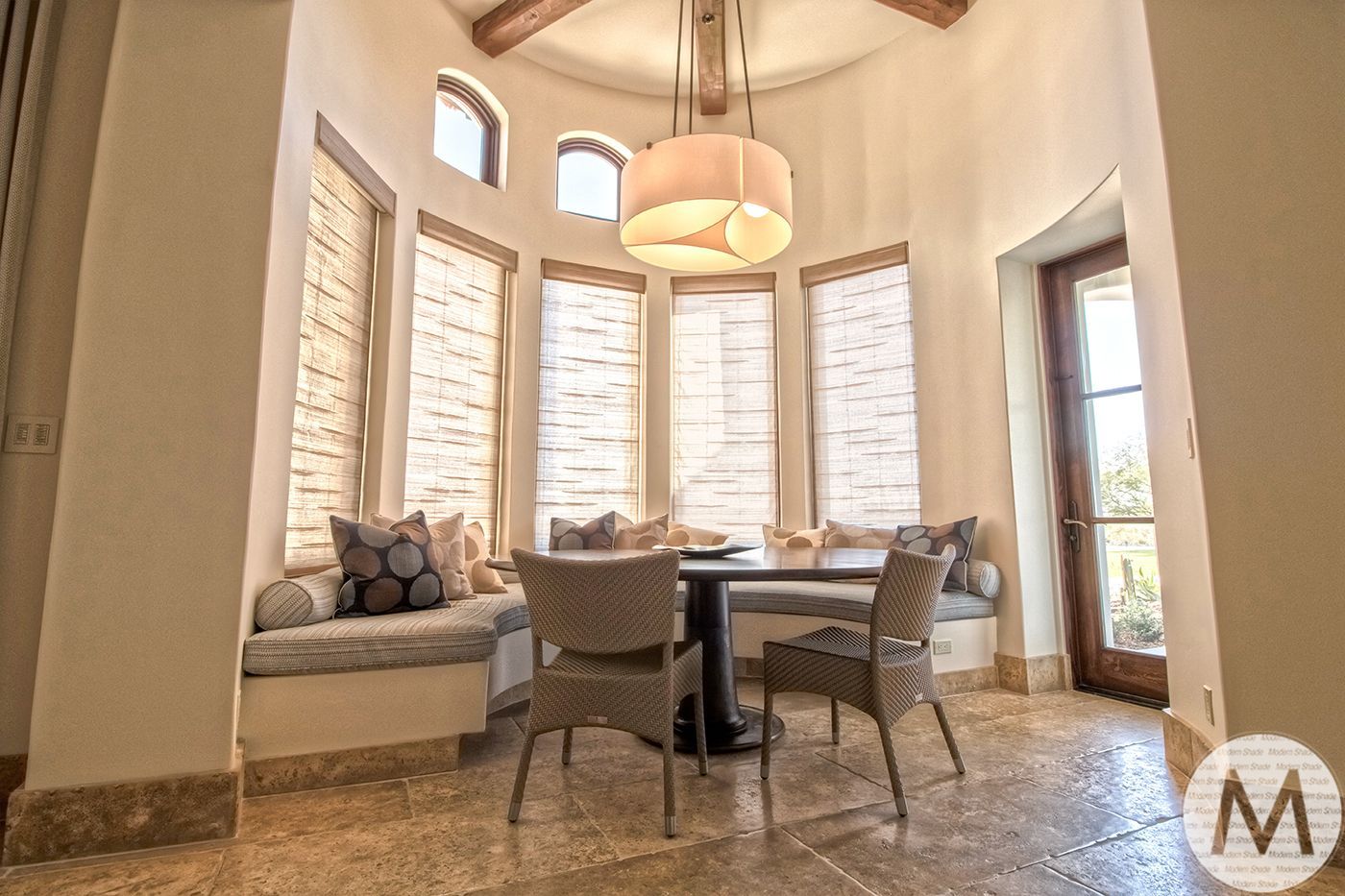Dining area with round table, built-in bench seating by windows, and hanging light.