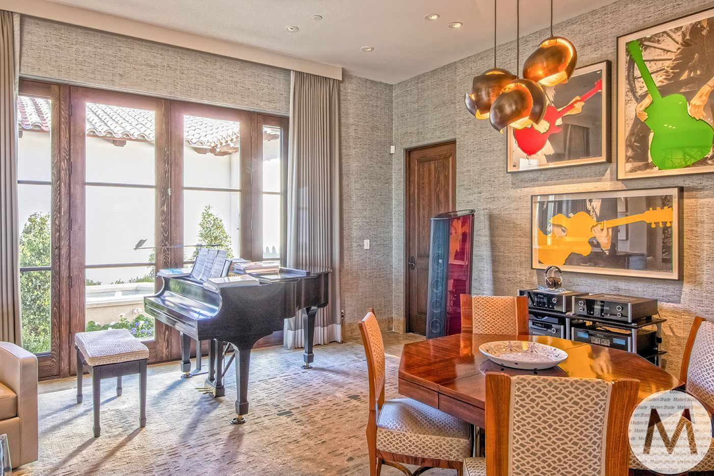 A dining area with a piano, art, round table, and large window with natural light.