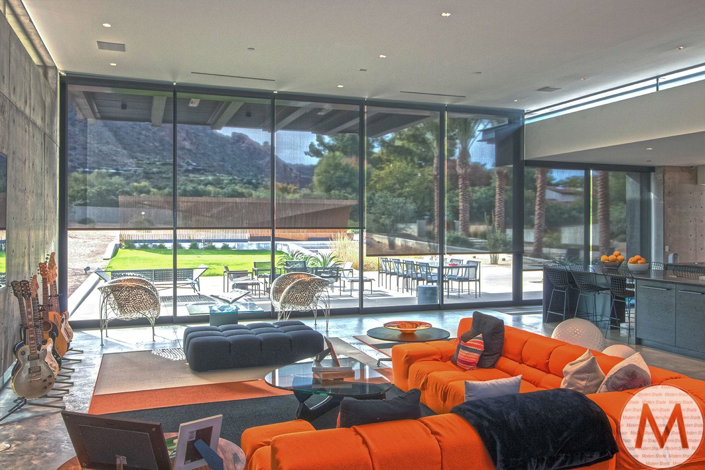 Living room with orange couch, floor-to-ceiling windows, and mountain view.