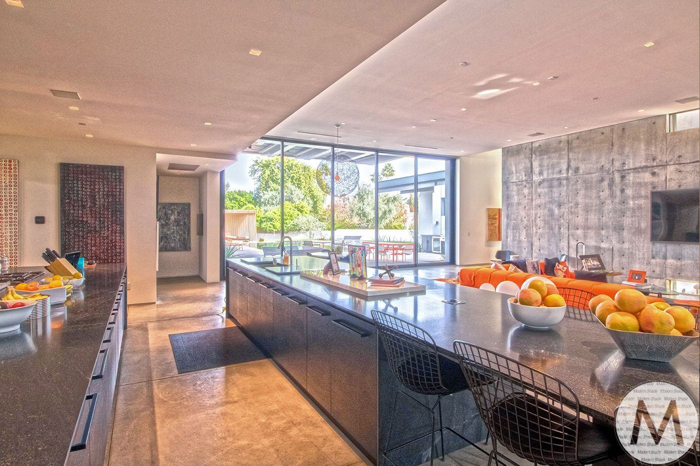 Modern kitchen with large island, black counters, and expansive window looking out to a patio.