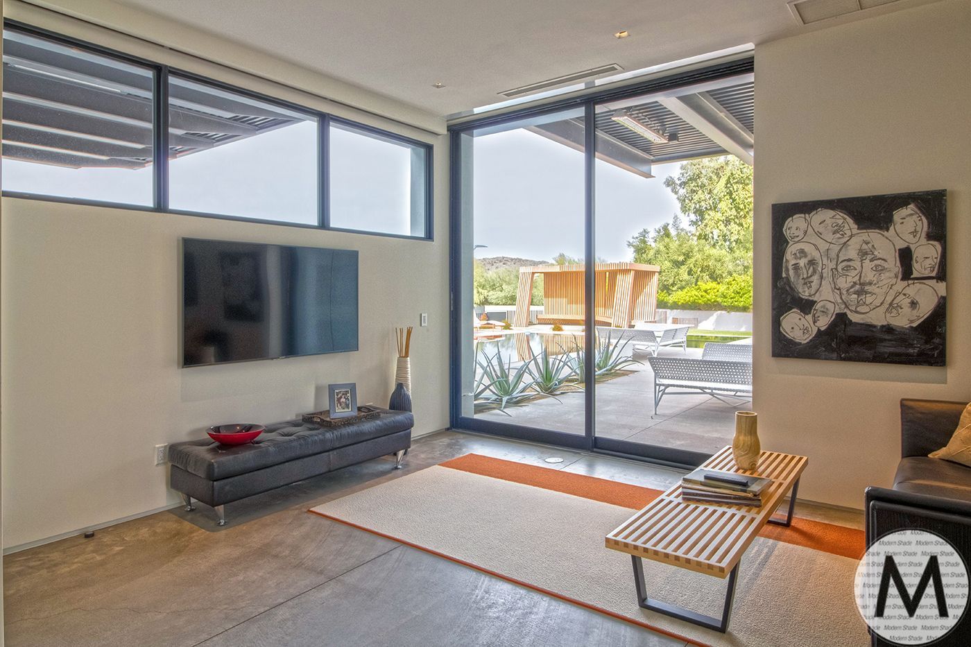 Living room with large windows, television, modern furniture, and outdoor patio view.